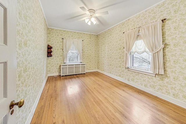 empty room with wood-type flooring, radiator, ceiling fan, and ornamental molding