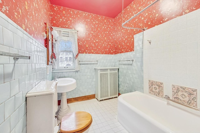 bathroom featuring tile walls, radiator heating unit, tile patterned floors, a tub, and toilet