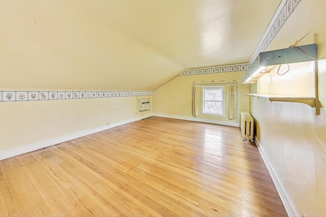 bonus room with hardwood / wood-style flooring, lofted ceiling, radiator, and a wall mounted AC