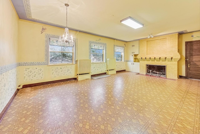 unfurnished living room featuring a chandelier, ornamental molding, a fireplace, and radiator