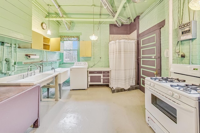 kitchen with washer / dryer, pendant lighting, white range with gas stovetop, and sink