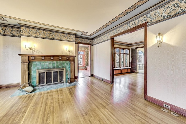 unfurnished living room featuring wood-type flooring, ornamental molding, and a tile fireplace