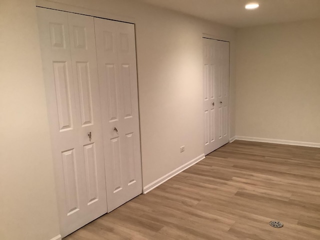 unfurnished bedroom featuring light wood-type flooring and two closets