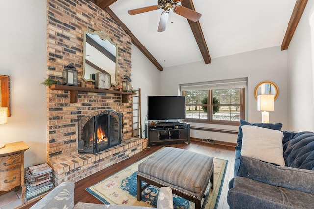 living room with ceiling fan, hardwood / wood-style flooring, vaulted ceiling with beams, and a brick fireplace