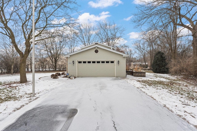 view of snowy exterior with an outbuilding and a garage