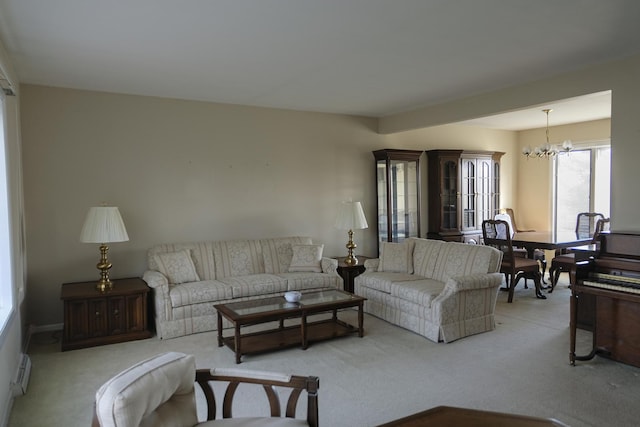 living room with a baseboard radiator, light colored carpet, and a notable chandelier