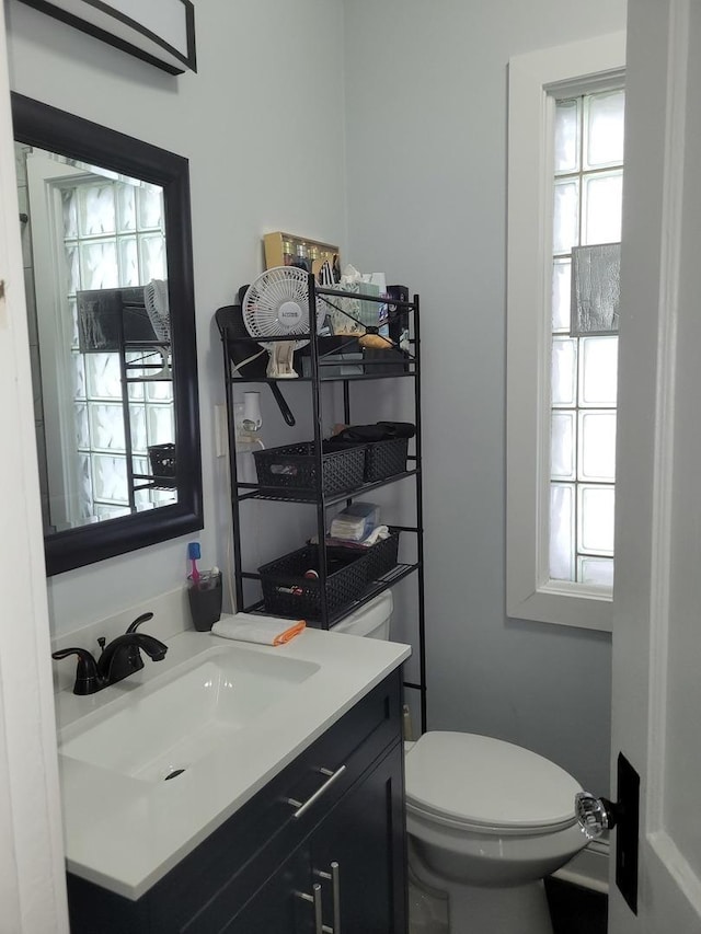 bathroom with toilet, a wealth of natural light, and vanity