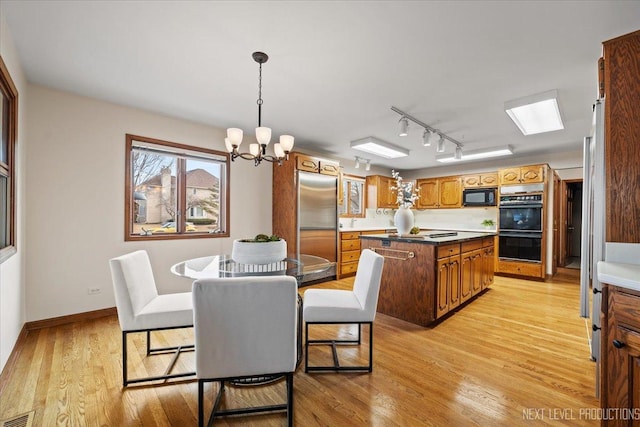 kitchen with a notable chandelier, visible vents, light wood-style flooring, a kitchen island, and black appliances