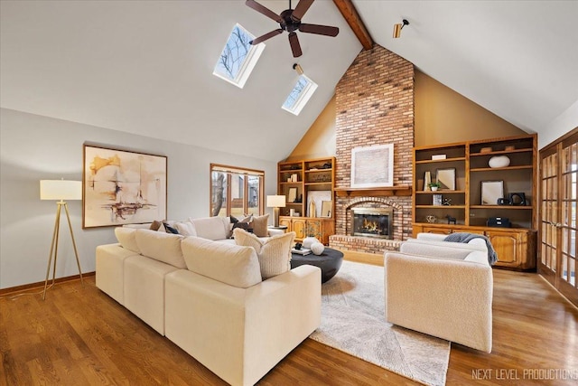 living area with beamed ceiling, a fireplace, wood finished floors, and a wealth of natural light