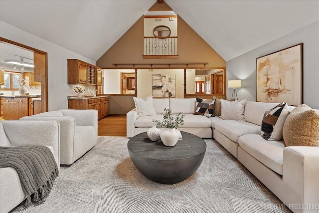 living area with high vaulted ceiling and light wood-style flooring