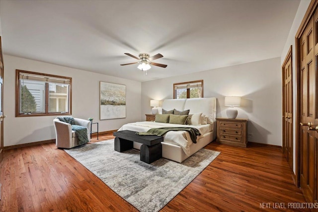 bedroom with a closet, dark wood-style flooring, ceiling fan, and baseboards