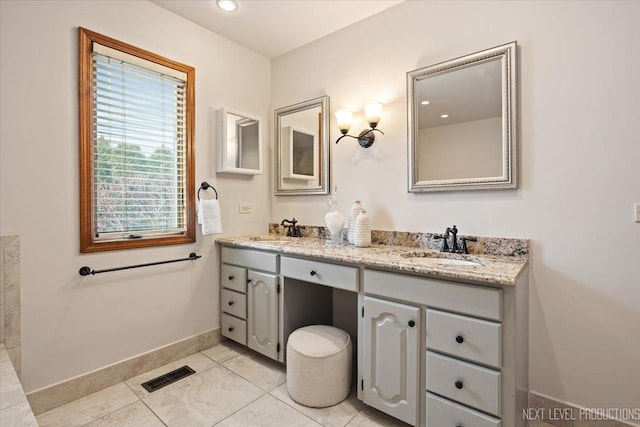 full bath featuring double vanity, baseboards, visible vents, and a sink