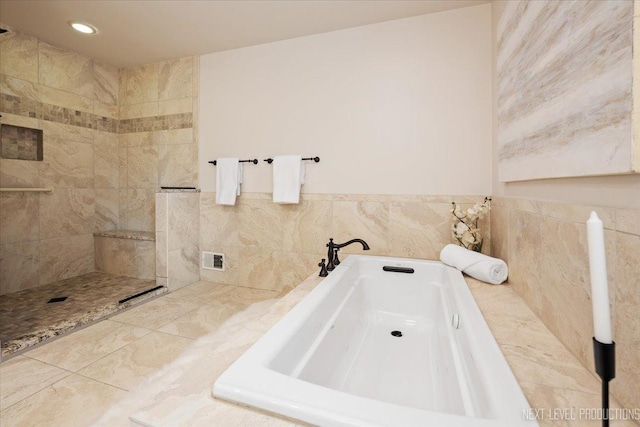 bathroom with a bathtub, recessed lighting, and tile walls