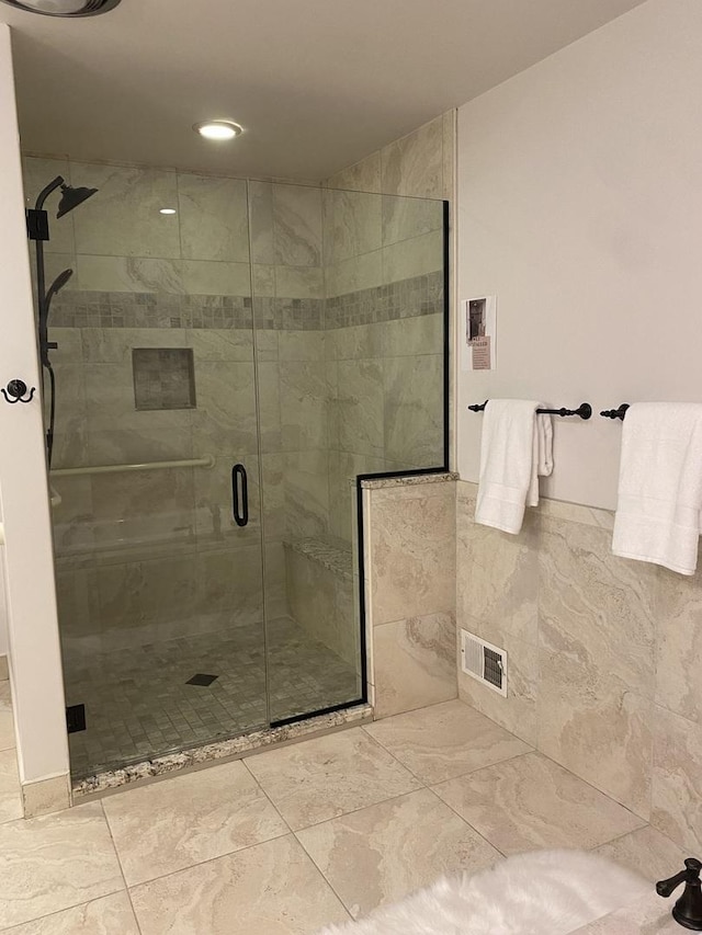 bathroom featuring a stall shower, visible vents, and tile walls