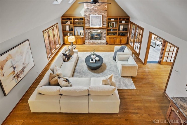 living room with baseboards, a ceiling fan, lofted ceiling, wood finished floors, and a fireplace