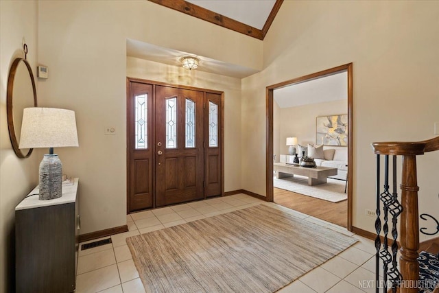 entryway featuring visible vents, a towering ceiling, baseboards, and light tile patterned floors