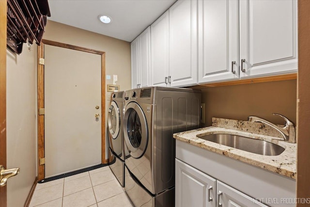 clothes washing area featuring light tile patterned floors, washing machine and clothes dryer, a sink, and cabinet space