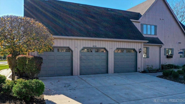 view of side of home with a shingled roof, driveway, and a garage