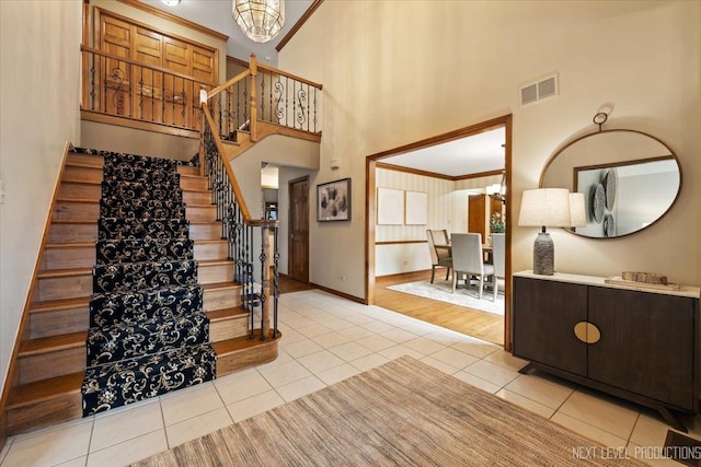 foyer entrance featuring light tile patterned floors, baseboards, visible vents, stairway, and ornamental molding