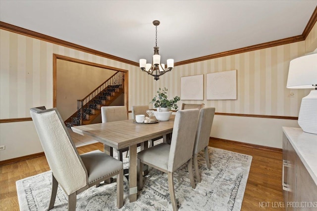 dining room featuring crown molding, baseboards, wood finished floors, and wallpapered walls