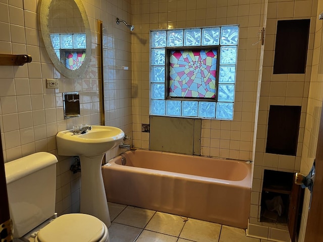 bathroom featuring tile walls, tiled shower / bath combo, tile patterned floors, and toilet