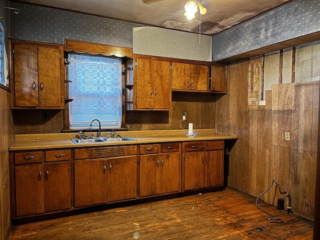 kitchen featuring sink, dark wood-type flooring, and wood walls