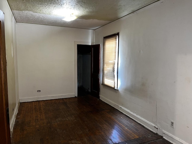 spare room featuring dark hardwood / wood-style flooring and a textured ceiling