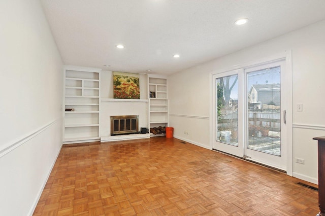 unfurnished living room featuring built in features and light parquet floors