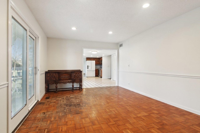 empty room with dark parquet flooring and a textured ceiling