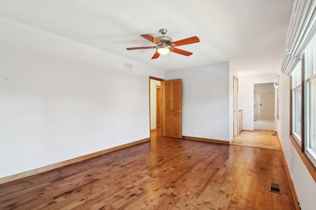 unfurnished room featuring ceiling fan, a textured ceiling, and light wood-type flooring