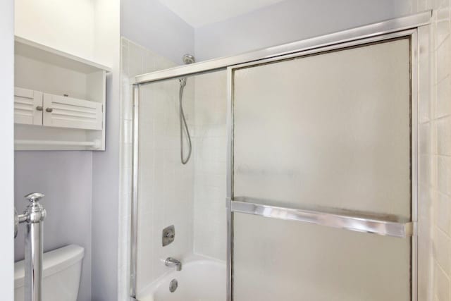 bathroom featuring enclosed tub / shower combo and toilet