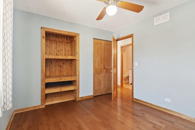 unfurnished bedroom with hardwood / wood-style flooring, ceiling fan, and a textured ceiling