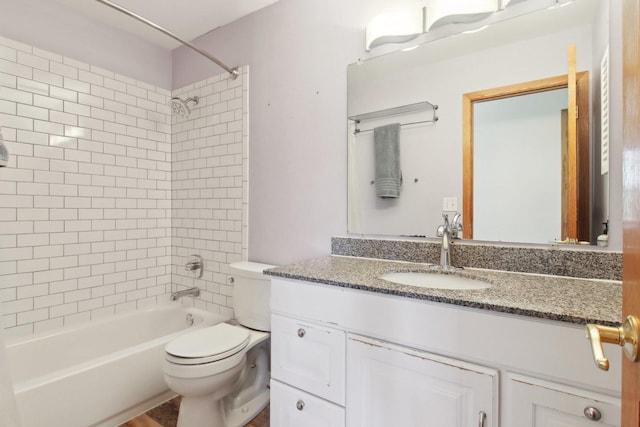 full bathroom featuring tiled shower / bath combo, vanity, and toilet