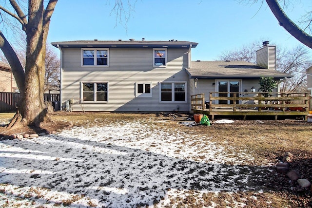 snow covered back of property with a wooden deck