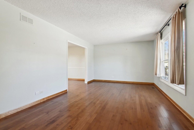 spare room with a textured ceiling and dark hardwood / wood-style flooring