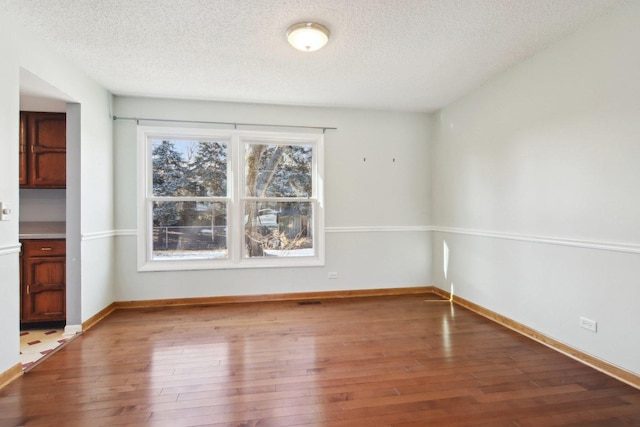 spare room with hardwood / wood-style floors and a textured ceiling