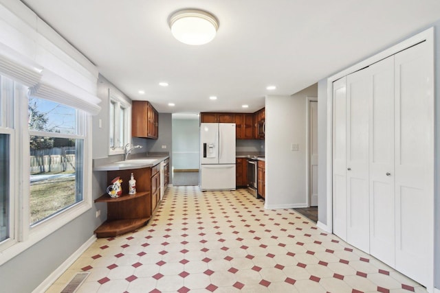 kitchen featuring white fridge with ice dispenser, sink, and stainless steel range with electric stovetop