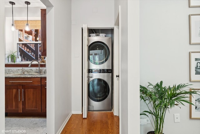 laundry area featuring wet bar, hardwood / wood-style floors, and stacked washer / dryer