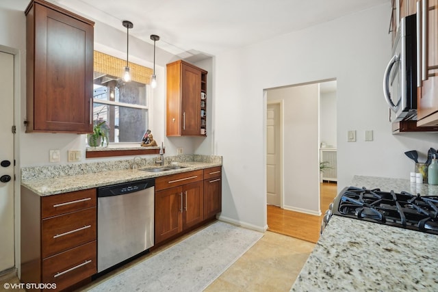 kitchen featuring pendant lighting, stainless steel appliances, light stone countertops, and sink