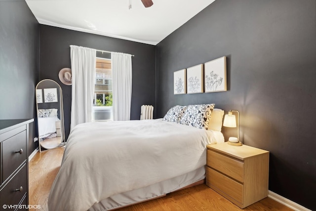 bedroom featuring ceiling fan, radiator heating unit, and light wood-type flooring