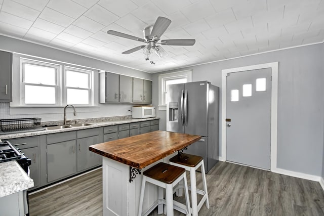 kitchen featuring wood-type flooring, sink, gray cabinets, and stainless steel fridge with ice dispenser