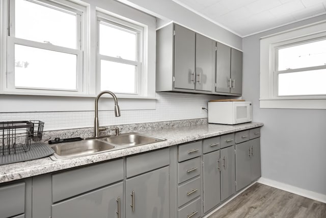 kitchen featuring crown molding, wood-type flooring, sink, and gray cabinetry