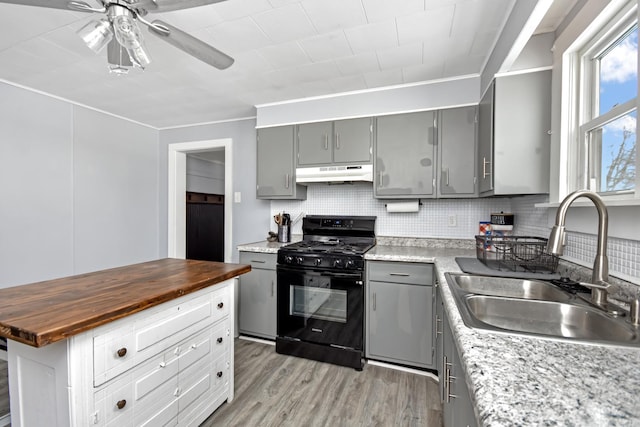 kitchen featuring sink, wooden counters, light wood-type flooring, ceiling fan, and black gas range