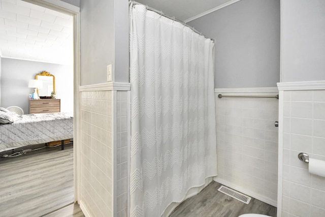 bathroom featuring hardwood / wood-style flooring, tile walls, and curtained shower