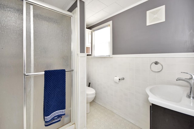 bathroom with tile walls, toilet, vanity, walk in shower, and crown molding