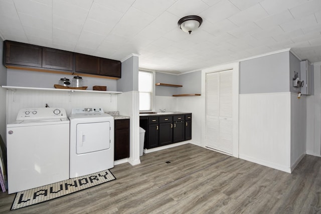 clothes washing area with sink, ornamental molding, light hardwood / wood-style floors, and washing machine and dryer