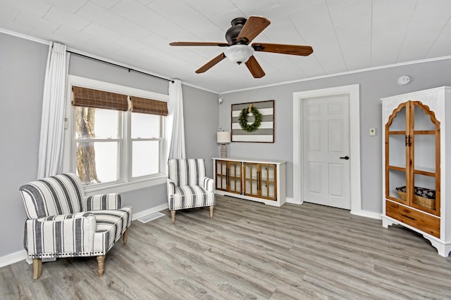 living area featuring crown molding, wood-type flooring, and ceiling fan