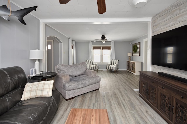 living room featuring ceiling fan, ornamental molding, and light hardwood / wood-style flooring