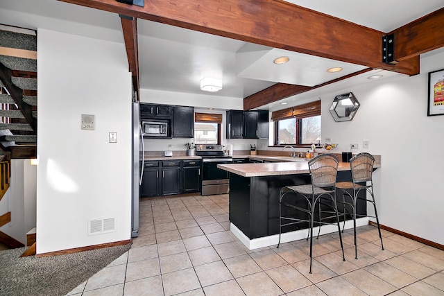 kitchen featuring a kitchen breakfast bar, light tile patterned floors, kitchen peninsula, beam ceiling, and electric stove