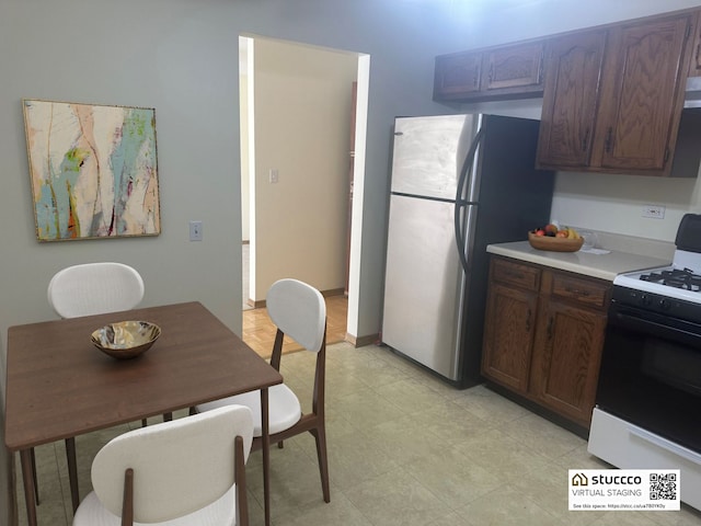 kitchen featuring dark brown cabinetry, range with gas stovetop, and stainless steel refrigerator